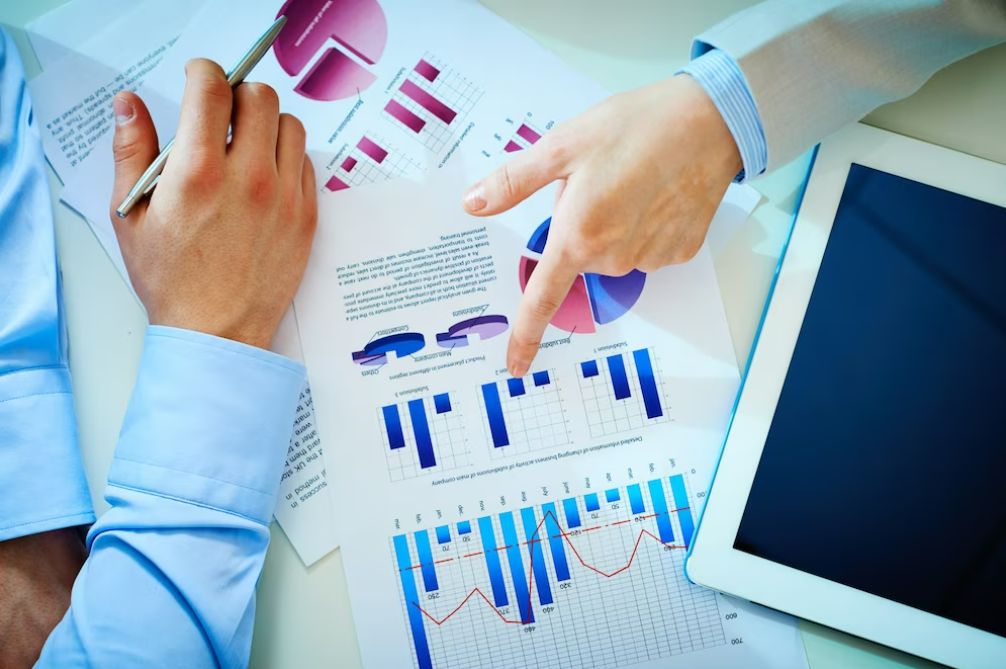 A person analyzing trading signals and pointing to a chart on a table.