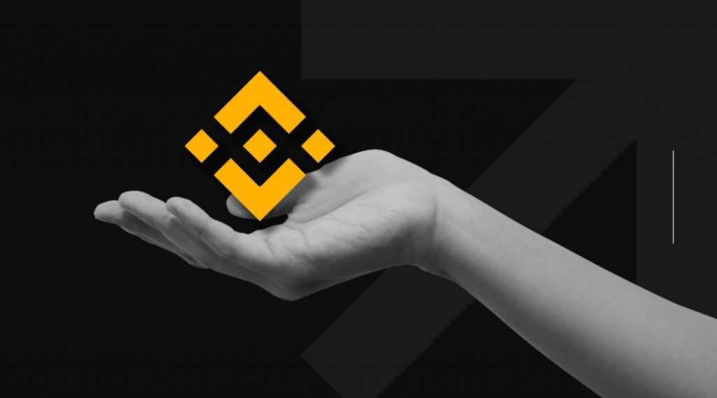 Binance exchange logo and a hand holding it