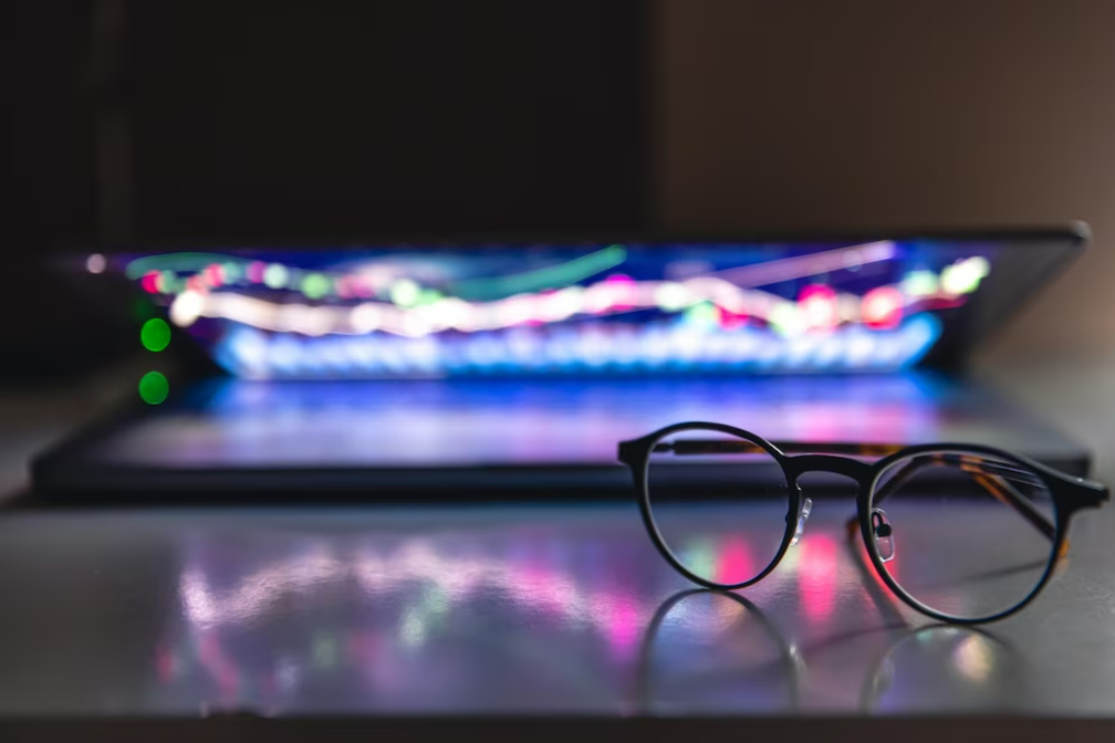 Portátil semicerrada con gráficos y estadísticas y lentes sobre una mesa