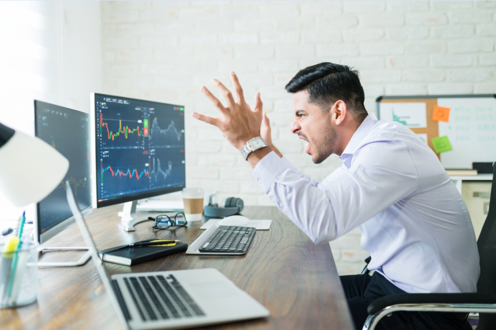 Hombre haciendo trading de criptomonedas gritando frente a su computadora.