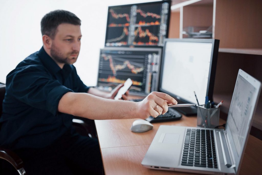 Hombre haciendo trading en Binance con varias pantallas en el fondo