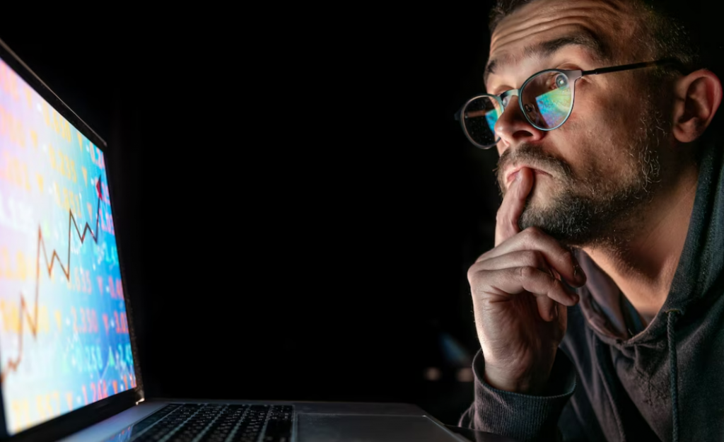 Man analyzing crypto chart patterns in front of a laptop