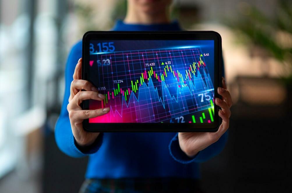 Persona sosteniendo una tableta digital con gráficos de acciones